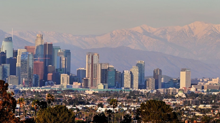 Snow-capped mountains are seen in the distance behind the Los Angeles skyline