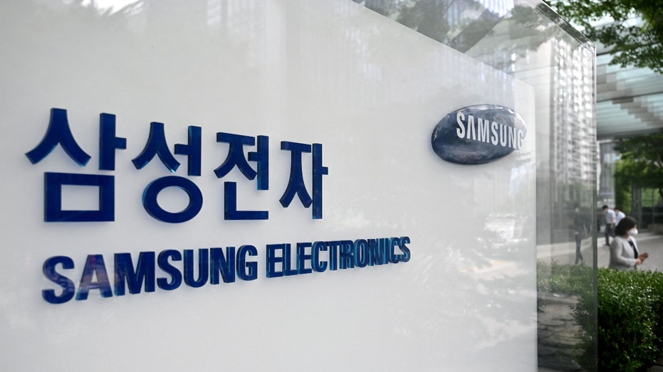 People walk past the logo of Samsung Electronics outside its Seoul building