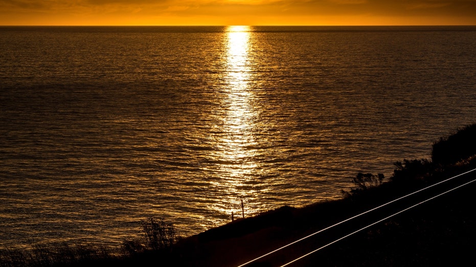 A sunset over the Pacific Ocean and California train tracks