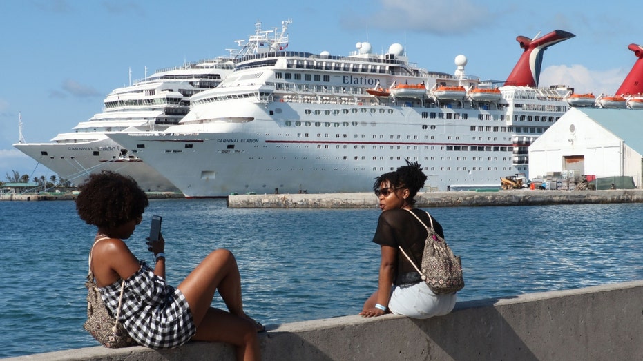 Two ladies take pictures in front of the Carnival cruise ship Elation in Nassau