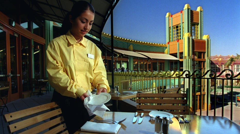 Waitress sets up a table at Catal Restaurant and Uva Bar at Downtown Disney