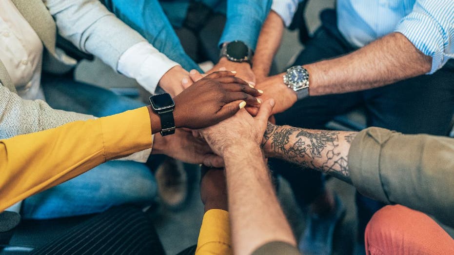 Unrecognizable multi ethnic business team holding their hands together. Modern business team holding hands like successful team.