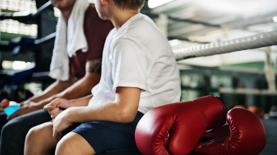 Boxing coach sits with kid