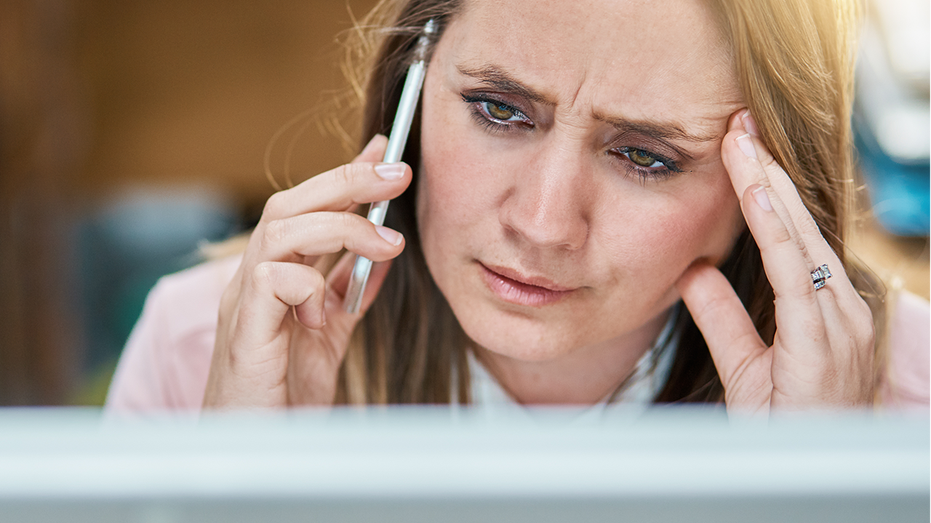 Frowning office worker talking or listening on mobile phone