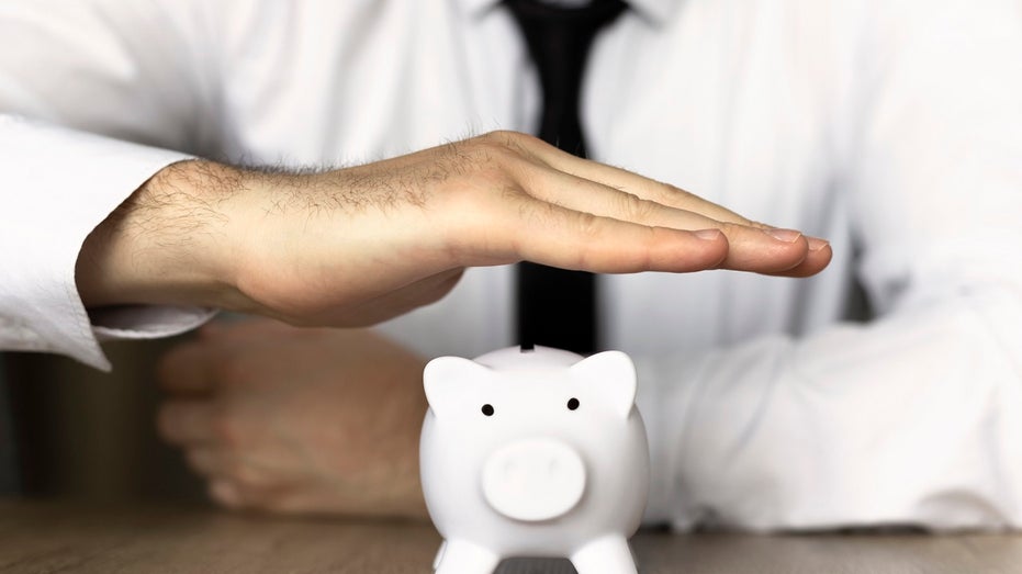 businessman with hand over piggy bank