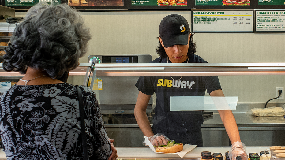 Subway employee makes a sandwich for a customer