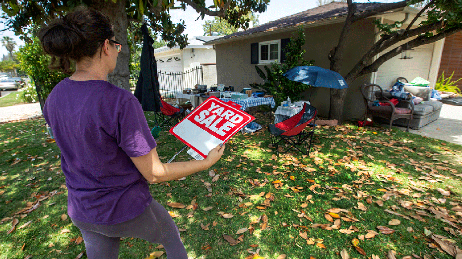 Person holding a yard sale sign