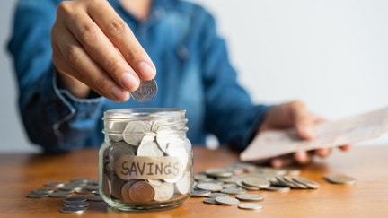 A person puts money into a retirement savings jar.