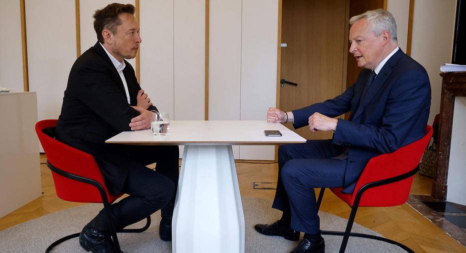 Elon Musk sits at a table to discuss matters