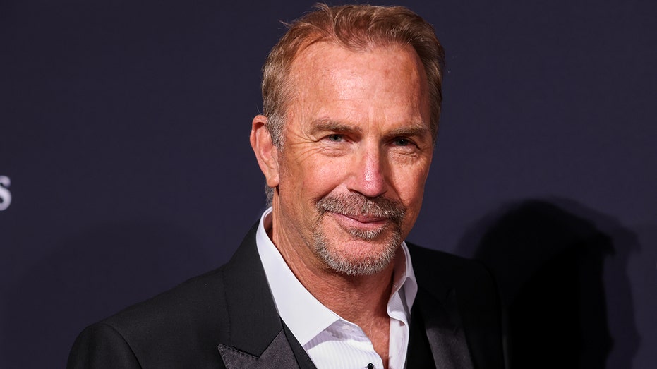 Kevin Costner soft smiles in a suit on the carpet for a Pre-GRAMMY Gala at The Beverly Hilton