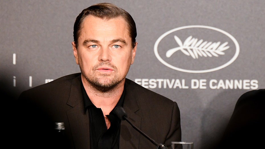 Leonardo DiCaprio stands behind a podium for press questions at Cannes Film festival