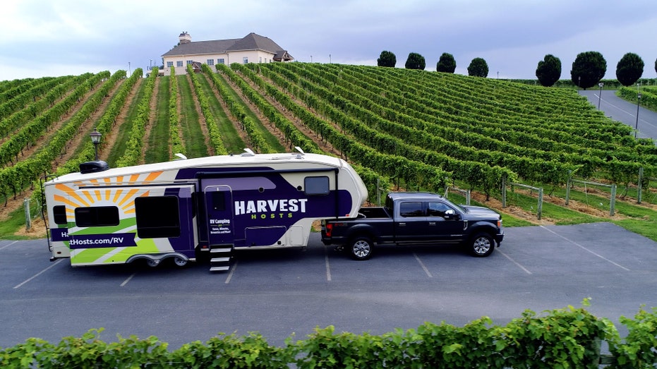 Truck pulling an RV behind it with the logo Harvest Hosts on it