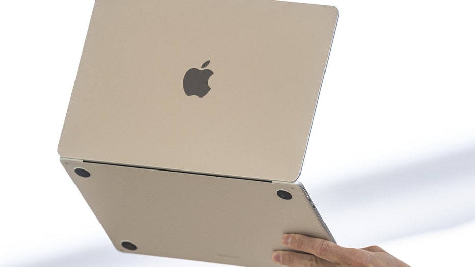 A person holds up a new MacBook Air laptop 