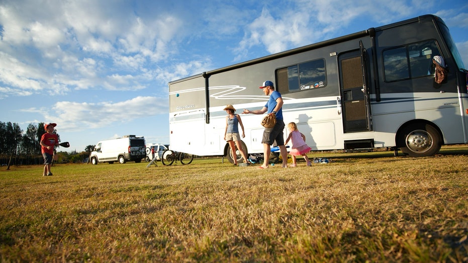 Family playing catch outside their RV