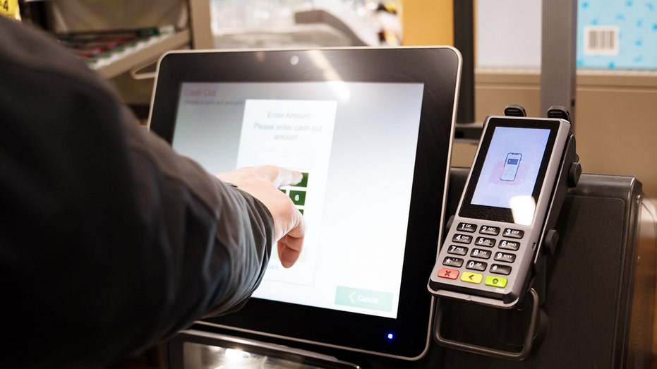 Persons hand clicking on self checkout machine