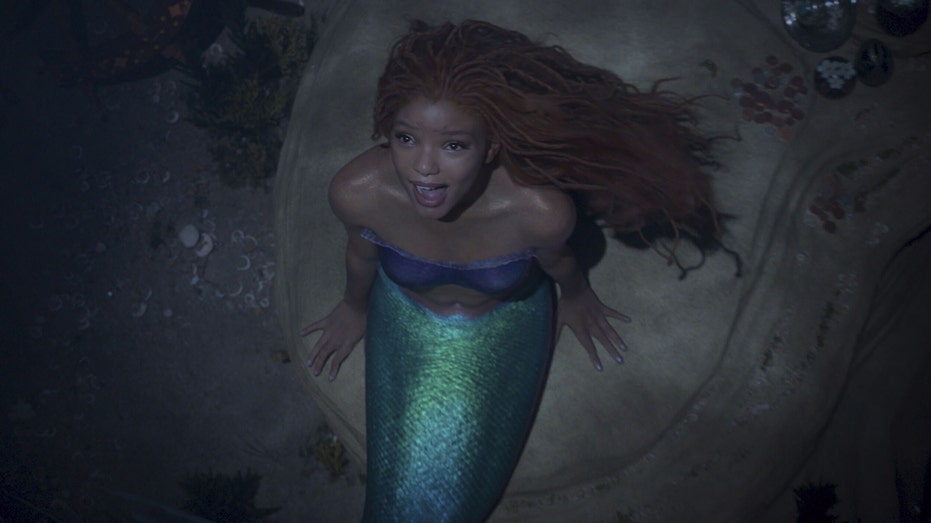 Halle Bailey as Ariel from The Little Mermaid singing up from beneath the water