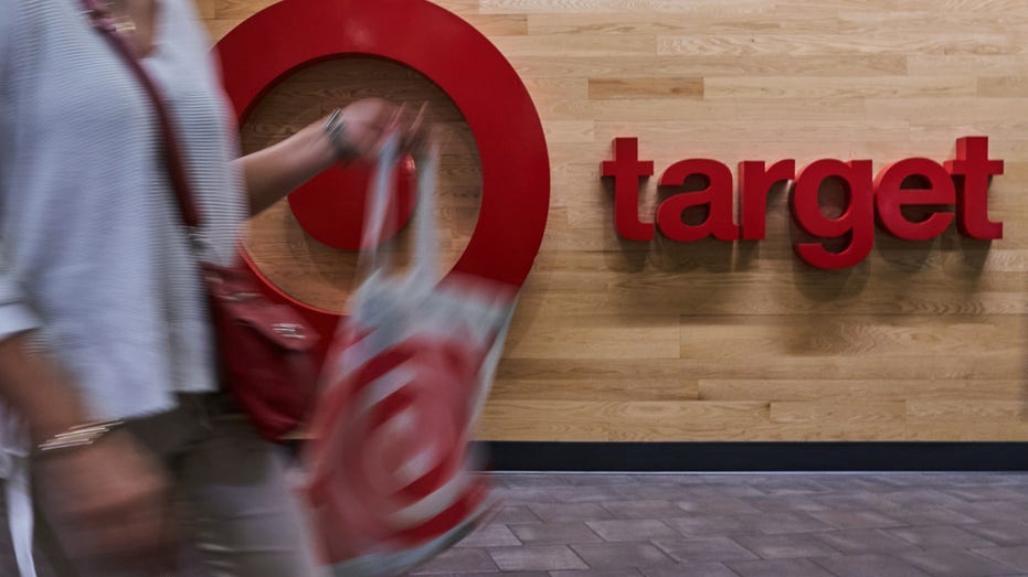A shopper carrying Target bags walks by the store logo