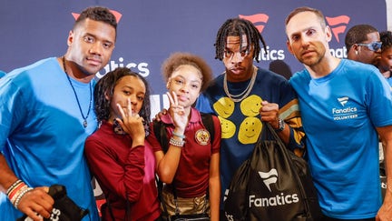 Fanatics CEO Michael Rubin, rapper Lil' Baby and Denver Broncos quarterback Russell Wilson pose with kids from Frederick Douglass Academy in Harlem during Merch Madness inaugural event on June 27, 2023. 