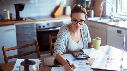 Close up of a young woman doing her bills in the kitchen