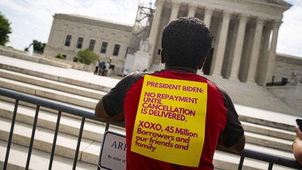 A visitor with a sign regarding student loan payments outside of the US Supreme Court in Washington, DC, US, on Tuesday, June 27, 2023. The Supreme Court is heading into its expected final week of the term for argued cases with a flurry of opinions on tap, including what could be a blockbuster on affirmative action in higher education and the fate of Joe Biden's student loan relief plan. Photographer: Al Drago/Bloomberg via Getty Images
