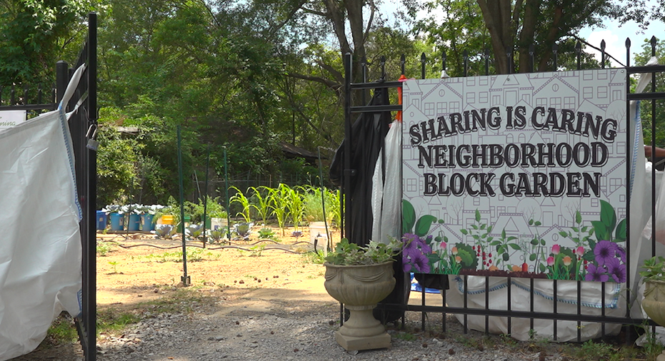outside entrance of garden. Sign on gate says "Sharing is Caring Neighborhood Block Garden"