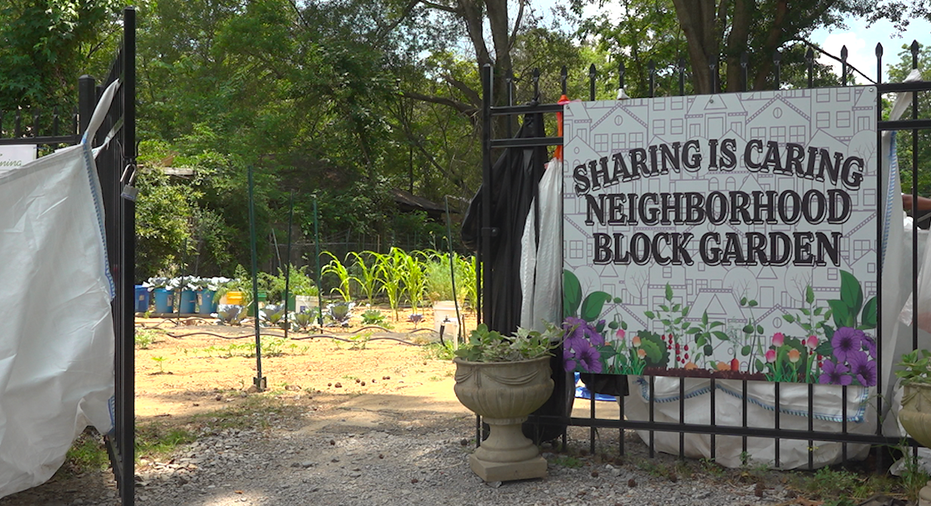 outside entrance of garden. Sign on gate says "Sharing is Caring Neighborhood Block Garden"