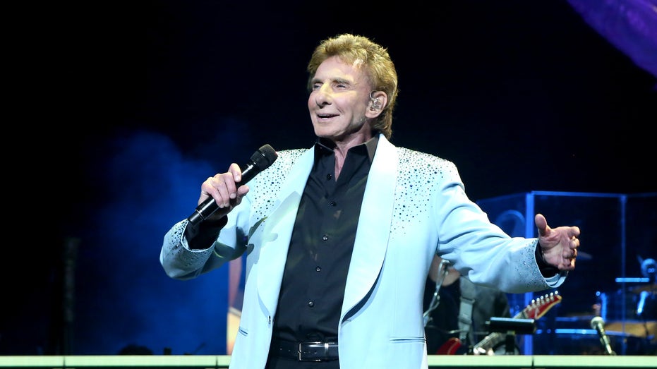 Barry Manilow performs on stage in a light blue jacket
