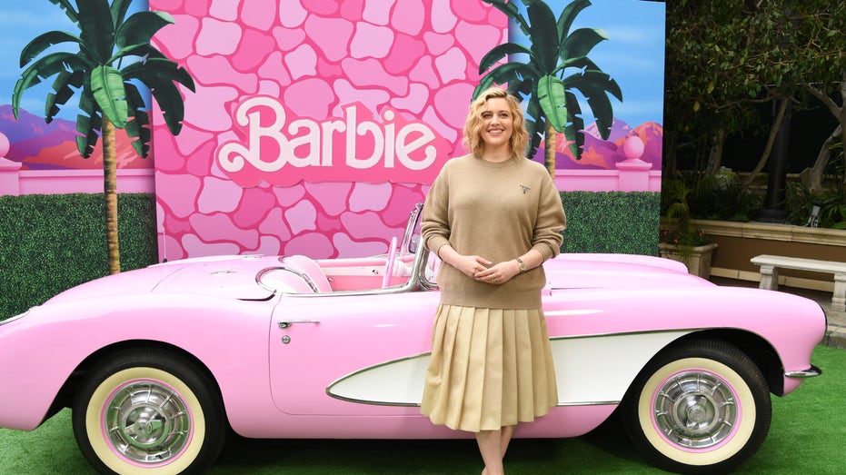 Greta Gerwig in front of a pink Barbie car