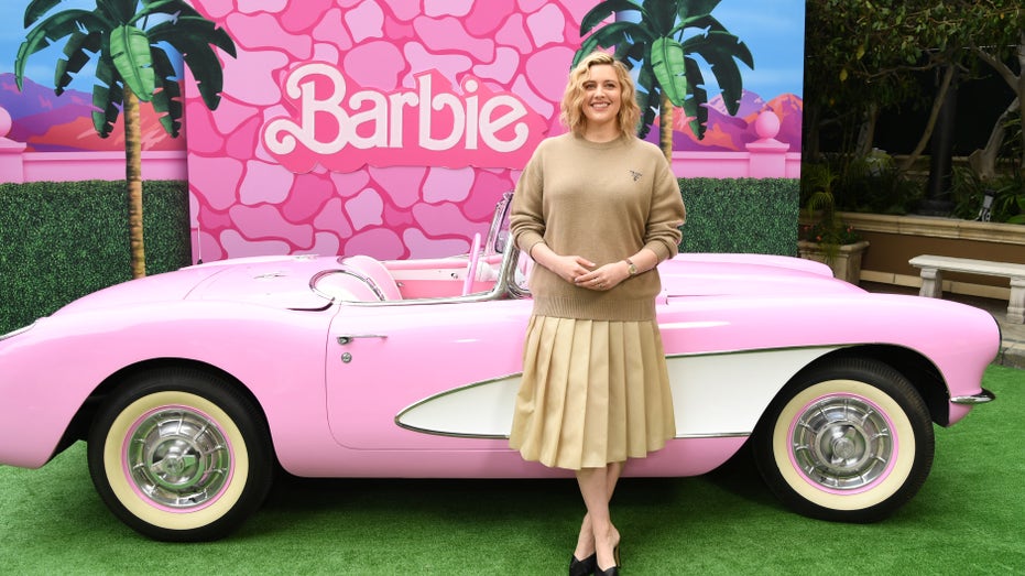 Greta Gerwig in front of a pink Barbie car