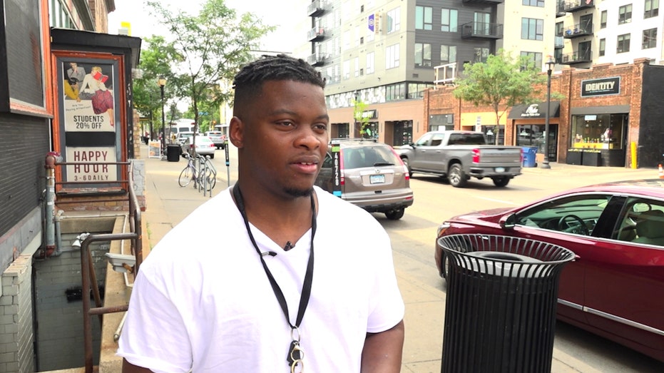 Man in white shirt speaking on sidewalk