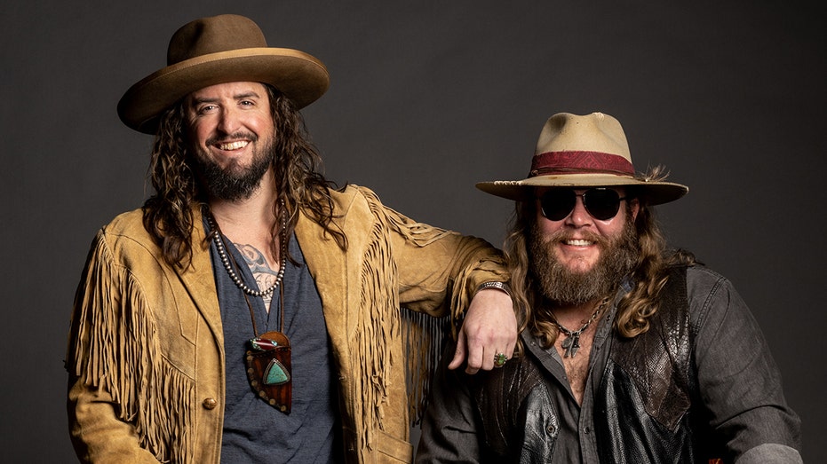 War Hippies Scooter Brown and Donnie Reis pose in leather jackets and cowboy hats