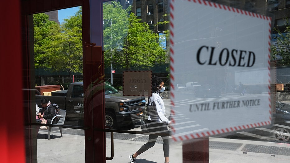 People walk passed a closed business in Brookly, New York, during the 2020 COVID-19 pandemic