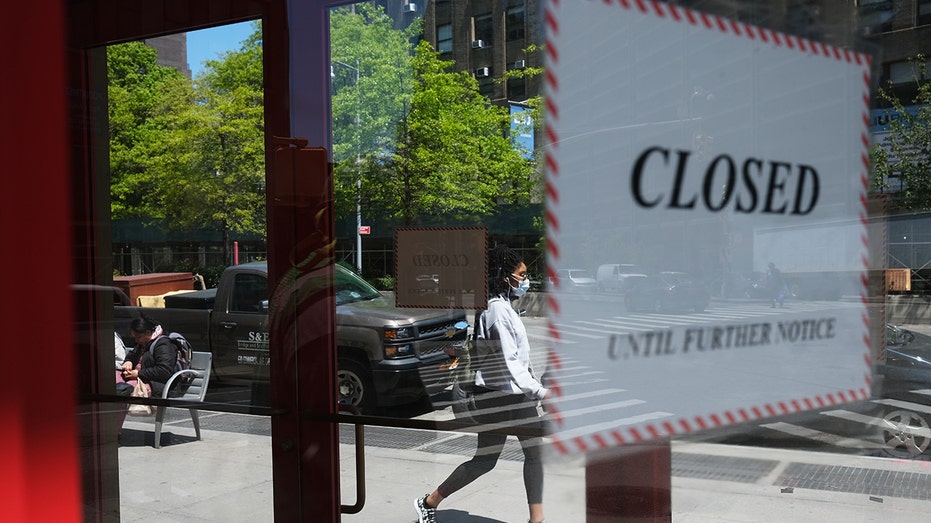 People walk passed a closed business in Brookly, New York, during the 2020 COVID-19 pandemic