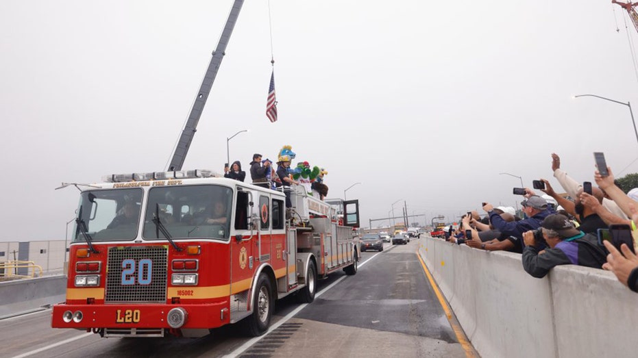 A firetruck carrying an American flag drives over the reconstructed portion of Interstate 95