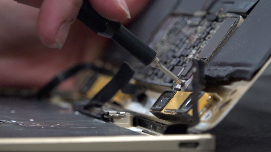 someone uses tweezers to pick at a computer hard drive