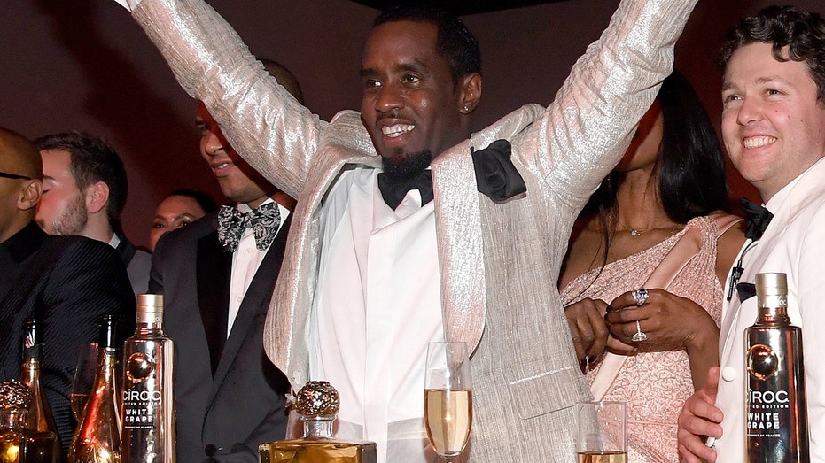 Sean Combs standing behind Ciroq vodka products