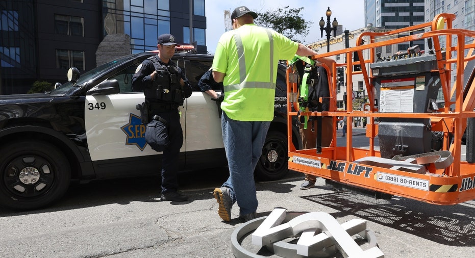 San Francisco police talk to a worker who was removing letters from the Twitter sign
