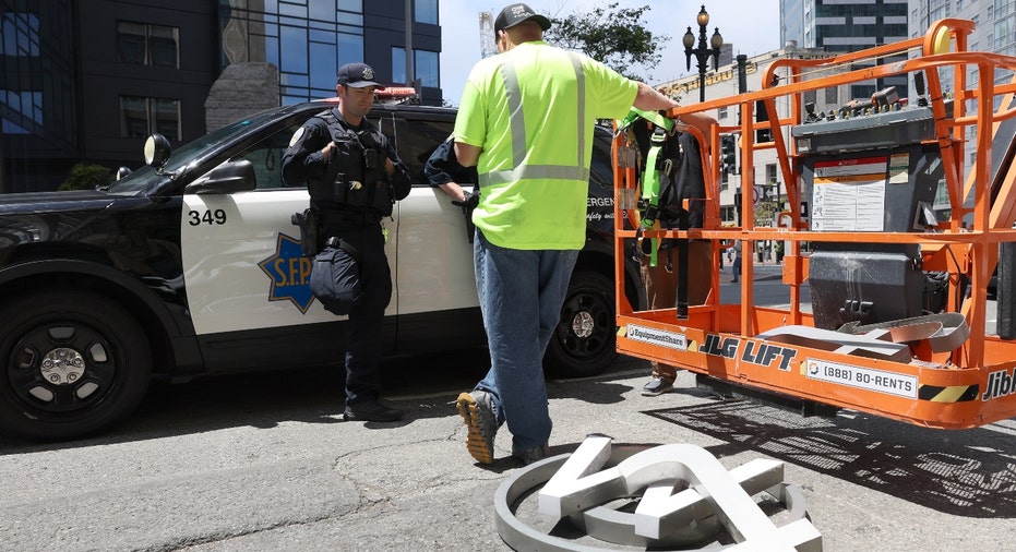 San Francisco police talk to a worker who was removing letters from the Twitter sign