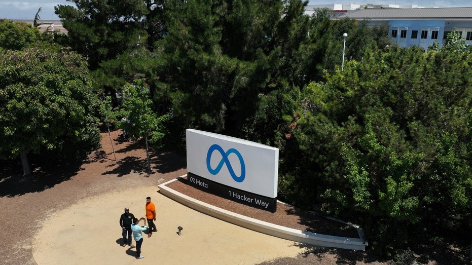 People in front of a sign for Meta headquarters