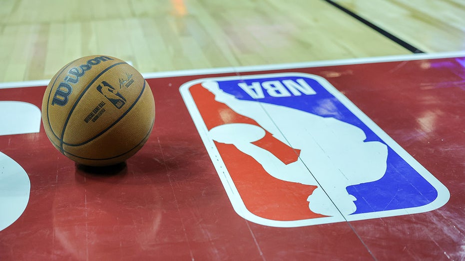A basketball on the court next to the NBA logo