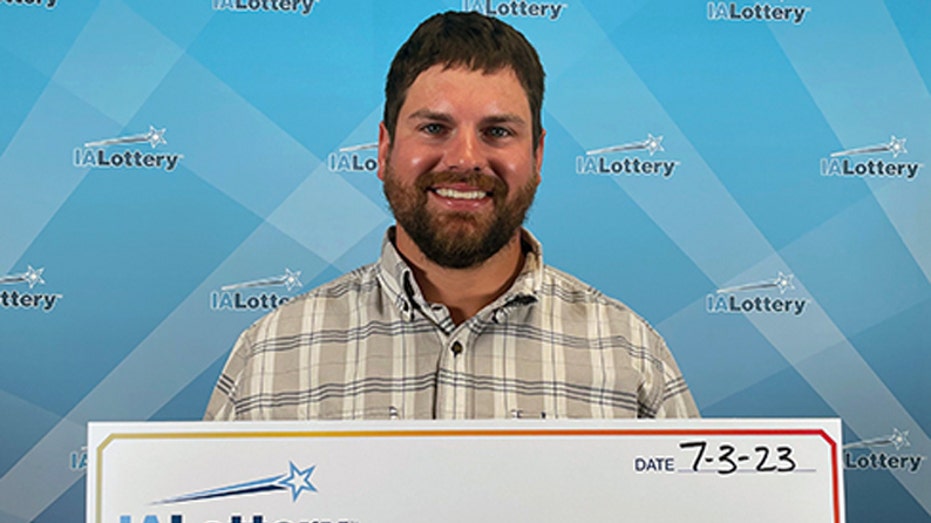 Nicholas Miller holds up Iowa Lottery check.