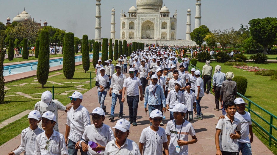 tourists walk in front of Taj Mahal