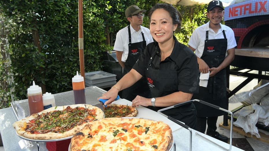 Ann Kim smiling next to pizza