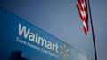 An American flag flies near signage displayed outside of the Walmart Stores Inc. headquarters building in Bentonville, Arkansas, U.S., on Wednesday, July 29, 2015. 