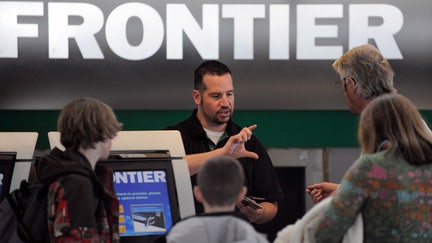 A Frontier Airlines employee helps customers check in at the Denver International Airport. 