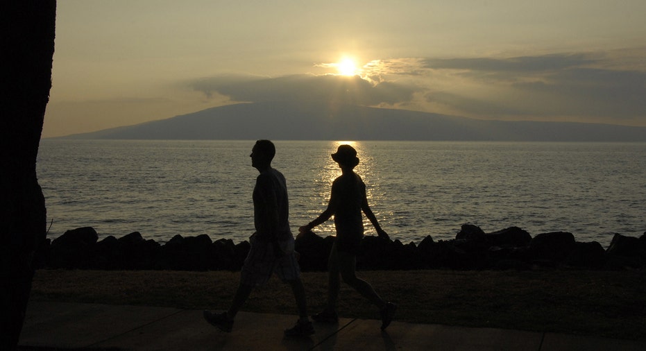 Couple walks along shoreline in Maui during sunset.