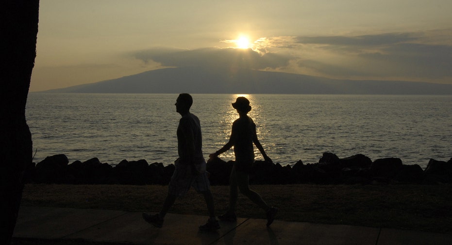 Couple walks along shoreline in Maui during sunset.