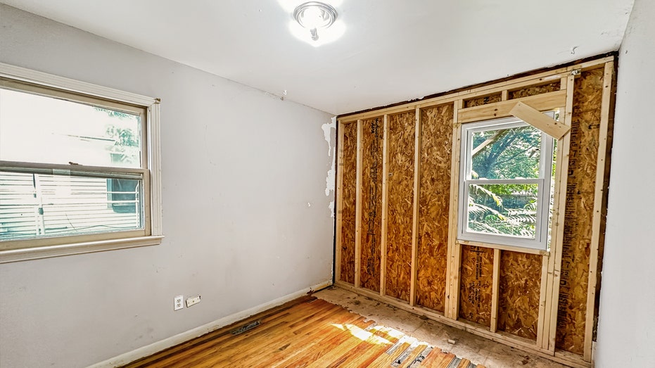 A bedroom with an exposed wall.