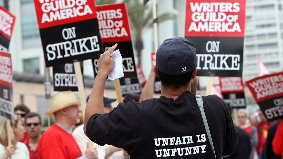 writers striking, holding picket signs