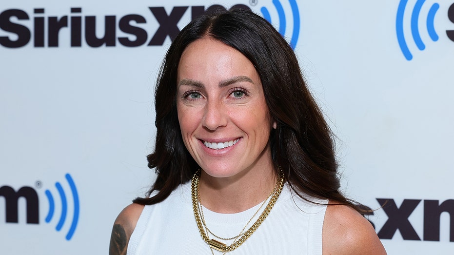 A close-up of Kelsi Sheren in a white sleeveless blouse with gold jewelry